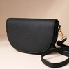 Vegan Leather Half Moon Crossbody Bag in Black on Beige Background