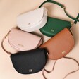 Pink, Green, Grey, Black and Tan Personalised Vegan Leather Half Moon Crossbody Bags on pink surface
