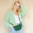 Model wearing the green Personalised Vegan Leather Half Moon Crossbody Bag with green cardigan