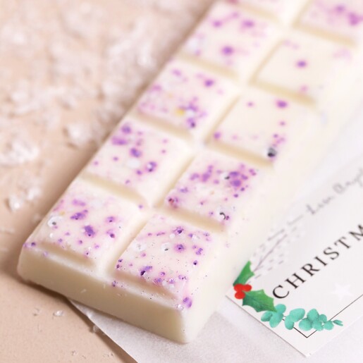 Close up of top of Lisa Angel Christmas Wreath Soy Wax Melts bar with packaging in background and fake snow
