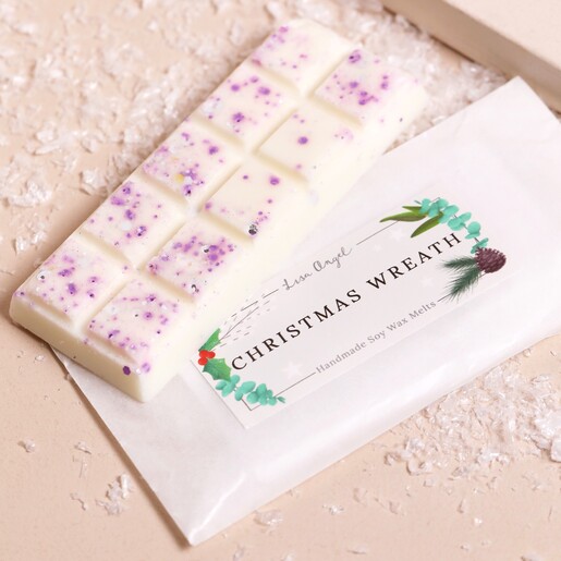 Lisa Angel Christmas Wreath Soy Wax Melts on top of packaging against beige backdrop with fake snow