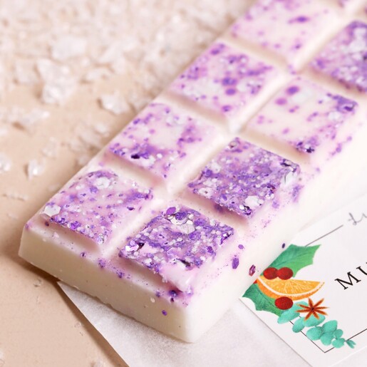 Close up of Lisa Angel Mulled Wine Soy Wax Melts on top of packaging with fake snow on beige backdrop