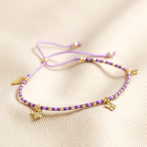 Full picture of Estella Bartlett Butterfly Charm Bracelet in Gold on beige fabric