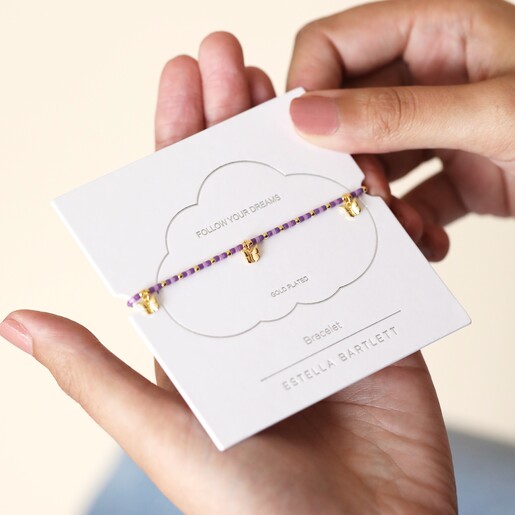 Estella Bartlett Butterfly Charm Bracelet in Gold on packaging and held in model's hands