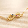 Close Up Estella Bartlett Multicoloured Crystal Infinity Bracelet In Gold on Beige Fabric