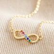 Close Up of Pendant on Estella Bartlett Multicoloured Crystal Infinity Pendant Necklace in Gold on Beige Fabric