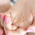 Estella Bartlett Multicoloured Crystal Infinity Pendant Necklace in Gold in Model's Hands