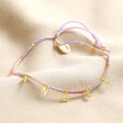 Estella Bartlett Pink Miyuki Bead Angel Charm Bracelet on top of beige coloured fabric