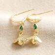 Estella Bartlett Green Crystal Bee Drop Hoop Earrings in Gold on top of beige coloured fabric