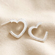 Estella Bartlett Crystal Heart Hoop Earrings in Silver on beige fabric