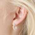 Close up of blonde model wearing the Estella Bartlett Crystal Heart Hoop Earrings in Silver