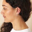 Model wearing the Estella Bartlett Crystal Heart Hoop Earrings in Silver as part of a curated ear