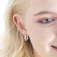 Blonde model wearing the Estella Bartlett Flat Wave Hoop Earrings in Silver