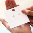 Estella Bartlett Kiss Stud Earrings In Gold on Packaging in Model's Hand