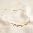 Full Chain of Estella Bartlett Ditsy Flower Miyuki Charm Necklace in Gold on Beige Fabric