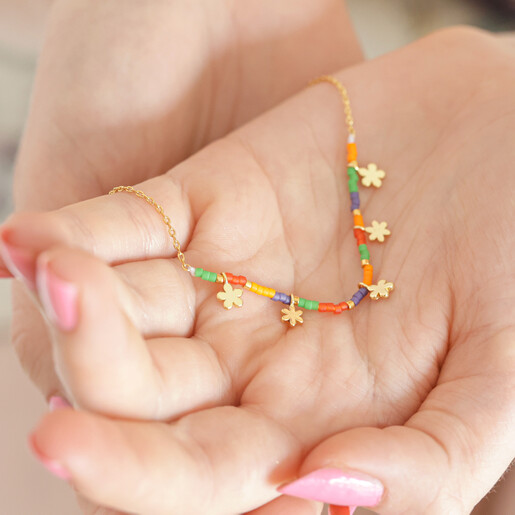 Estella Bartlett Ditsy Flower Miyuki Charm Necklace in Gold in Model's Hands