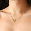 Close up of Estella Bartlett Green Crystal Floral Bee Pendant Necklace in Gold on model with dark hair