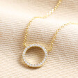 Estella Bartlett Pave Circle Pendant Necklace in Gold on beige fabric