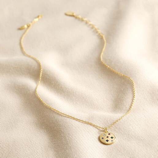 Full Chain of Estella Bartlett Multicoloured Crystal Disc Pendant in Gold on Beige Fabric 