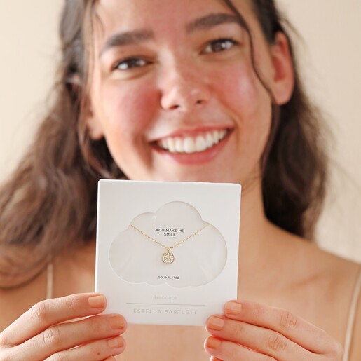 Estella Bartlett Pavé Smiley Pendant Necklace Gold in Packaging Held by Model
