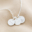 Close Up of Estella Bartlett Triple Disc Charm Necklace In Silver on Beige Fabric