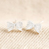 Sterling Silver Tiny Bow Stud Earrings on Beige Fabric