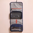 Gentlemen's Hardware Roll Up Travel Wash Bag open on top of beige coloured backdrop