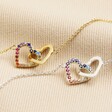 Interlocking Rainbow Crystal Heart Bracelet in Silver with gold version on beige coloured fabric