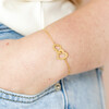Model Wearing Interlocking Heart Charm Bracelet in Gold with Hand in Pocket