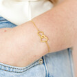 Model Wearing Interlocking Heart Charm Bracelet in Gold with Hand in Pocket