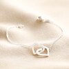 Interlocking Heart Charm Bracelet in Silver on Beige Fabric