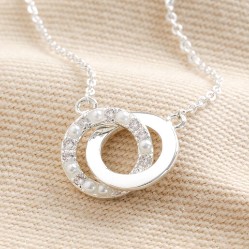 Close Up of Interlocking Pearl and Crystal Hoops Bracelet in Silver on Beige Fabric