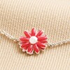 Close Up of Charm on Pink Enamel Daisy Charm Bracelet in Silver on Beige Fabric