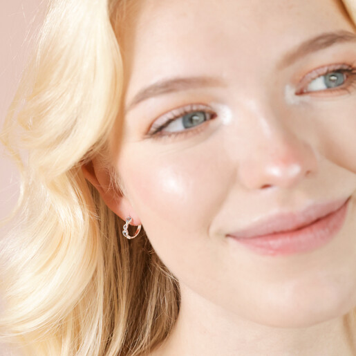Model smiling wearing Blue Crystal Heart Huggie Hoop Earrings in Silver