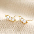 Pearl Three Peas in a Pod Stud Earrings in Gold on neutral coloured fabric