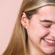 Model laughing wearing Pink Enamel Daisy Stud Earrings in Silver in front of neutral backdrop
