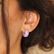 Close Up of Purple Resin Domed Huggie Hoop Earrings on Model