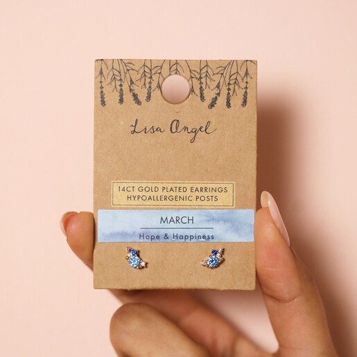 Earrings in Packaging Model holding Birthstone Cluster Stud Earrings in Silver in front of pink wall