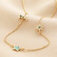 Green Enamel Star Sun and Moon Charm Necklace in Gold arranged on neutral coloured material