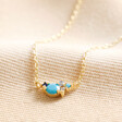 December Birthstone Cluster Necklace in Gold on Beige Fabric