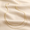Full Chain of Double Ball Chain Necklace in Gold on Beige Fabric