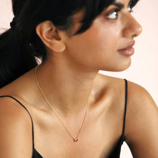 Model looking to side wearing Red Stone Heart Pendant Necklace in Gold