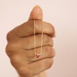 Model holding Red Stone Heart Pendant Necklace in Gold hanging over knuckles