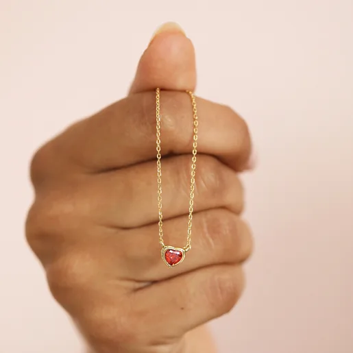 Model holding Red Stone Heart Pendant Necklace in Gold hanging over knuckles