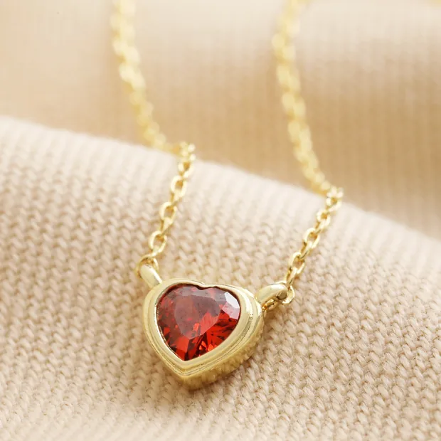 Red Stone Heart Pendant Necklace in Gold Red Stone Heart Pendant Necklace in Gold on neutral coloured fabric