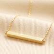Horizontal Bar Necklace in Gold on top of neutral coloured fabric