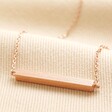 Horizontal Bar Necklace in Rose Gold on top of beige coloured fabric