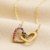Interlocking Crystal Hearts Necklace in Gold on Beige Fabric