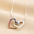 Interlocking Rainbow Crystal Hearts Necklace in Silver on top of beige coloured fabric