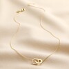 Interlocking Pearl and Crystal Hoops Necklace in Gold on top of beige fabric